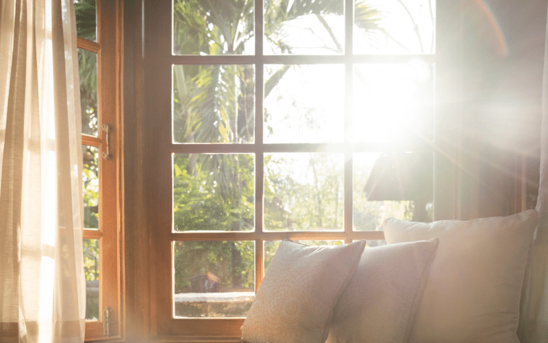 A classic living room featuring large wooden casement windows with a garden view.