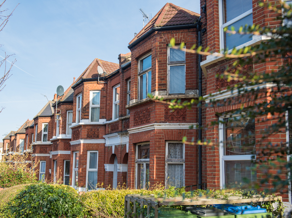 A row of red brick-finished houses with white casement windows