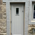 Hardwood entrance door with vertical grooves in Farrow and Ball Worsted