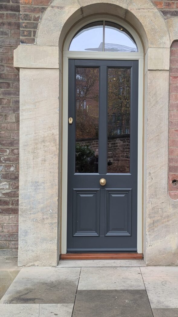 Hague Blue Accoya timber door with arched fanlight, aged brass hardware inside a decorative arched reveal