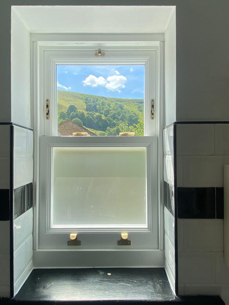 Box Sliding Sash bathroom window with obscure glass. The view looks out over Hebden Bridge hills on a summers day.