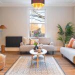 Living room with warm orange light, comfy sofas and timber sliding sash windows