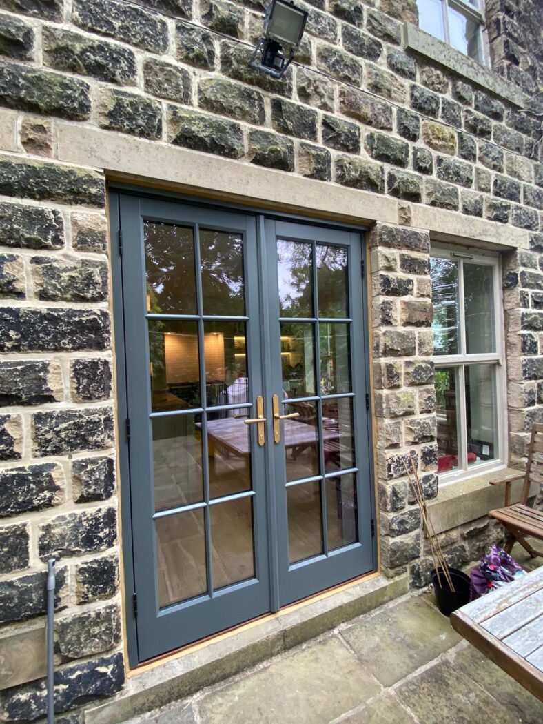 Rustic stone house with french patio doors in Farrow and Ball Down Pipe and brass handles.