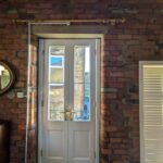 Wooden french balcony windows in a studio conversion bedroom with exposed brick