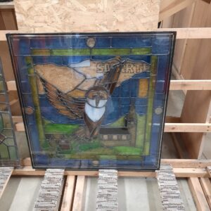 Decorative glass by Design Glass depicting an owl flying over a church with blue and green glass