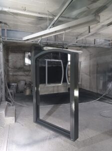 Arched window frame painted dark grey hanging to dry in the Patchett Joinery workshop