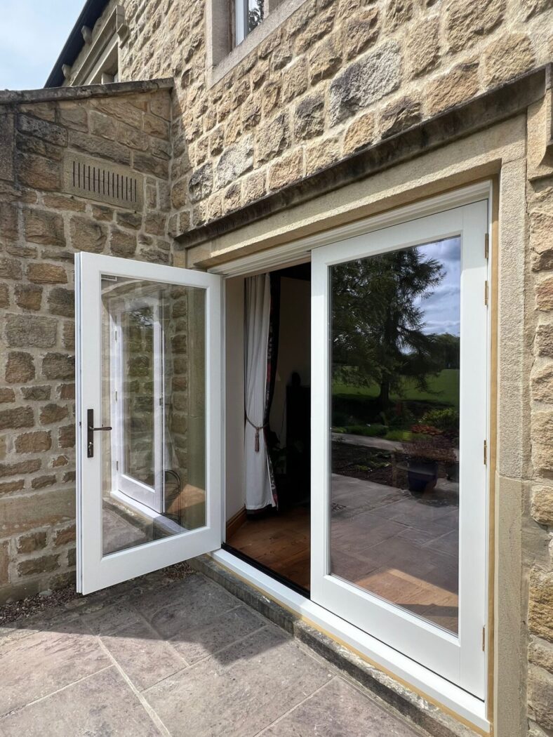 Grey stone patio with white timber double doors, with one door open.