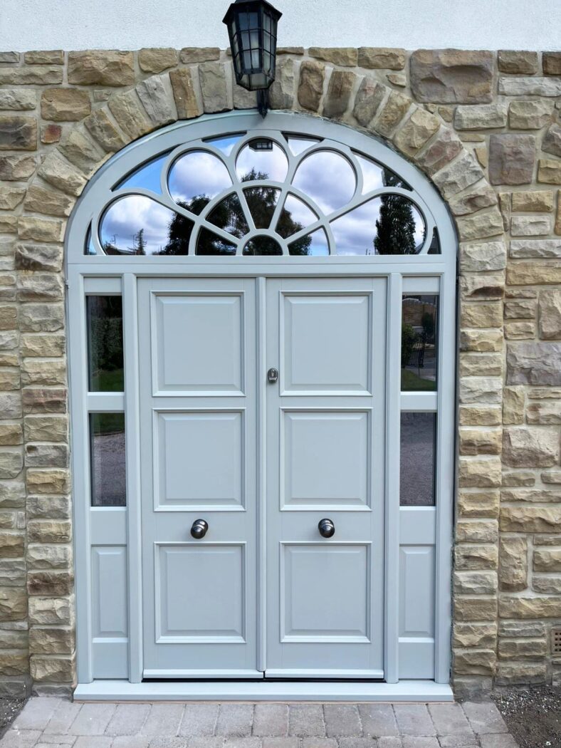 Ornate set of grey double doors with a patterned fanlight