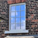 A traditional red brick British property with a weights and pulleys sash window