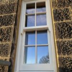White Sliding Sash window within a stone house with Georgian bars