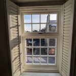 Sun shining through the interior of a Flush casement window with Georgian bars and venetian blinds