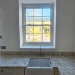 Traditional style Georgian sash window in a new kitchen with marble worktops.