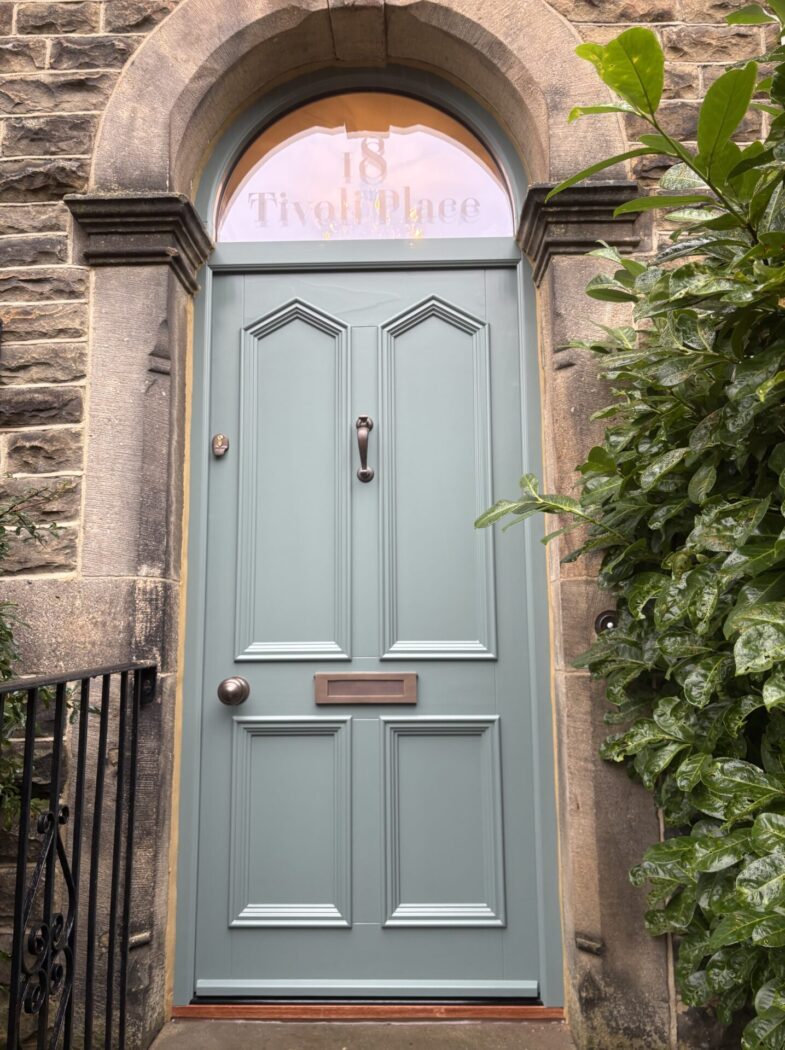 Large Accoya timber front door in Little Greene Livid with shaped door panels and a sandblasted arched fanlight reading '18 Tivoli Place'