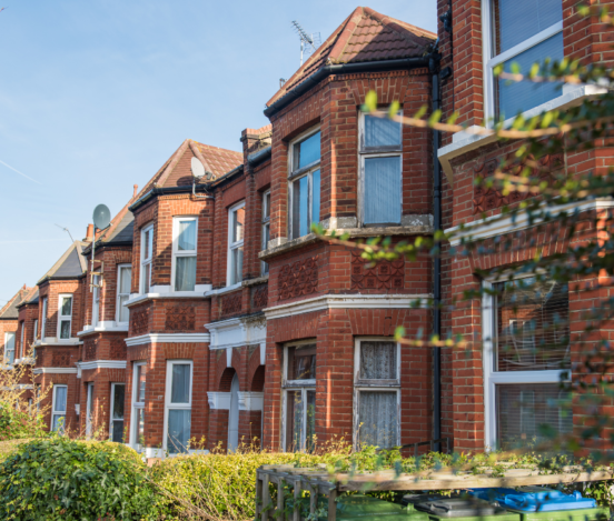 A row of red brick-finished houses with white casement windows