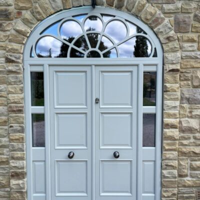 Ornate set of grey double doors with a patterned fanlight