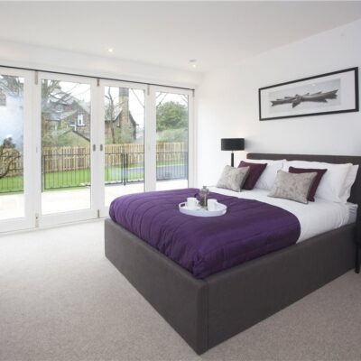 Bedroom with wooden bi-fold door in white and a bed with purple sheets
