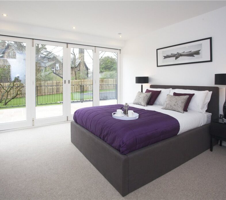 Bedroom with wooden bi-fold door in white and a bed with purple sheets