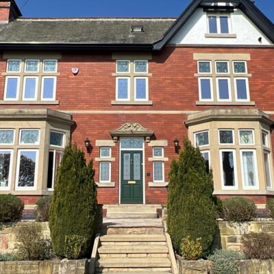 Large house in the UK with art deco style casement windows and a green timber front door